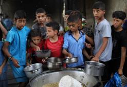 فلسطينيون يتجمعون لتلقي وجبات طعام من مطبخ خيري في مخيم النصيرات وسط قطاع غزة