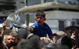 طفل يحاول الحصول على طعام مجاني جراء اشتداد المجاعة تشتد في غزة