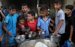 فلسطينيون يتجمعون لتلقي وجبات طعام من مطبخ خيري في مخيم النصيرات وسط قطاع غزة