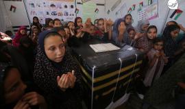 اطفال فلسطينيون نازحون يطوفون حول مجسم للكعبة المشرفة خلال فعالية تعريفية بمناسك الحج داخل خيمة في مركز ايواء النازحين في مستشفى شهداء الاقصى بدير البلح