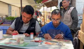 مواطنين يقومون بإصلاح عملات ورقية قديمة بمدينة غزة