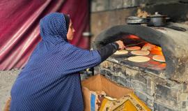 سيدة من غزة تعد الخبز على النار في ظل نقص الغاز والكهرباء