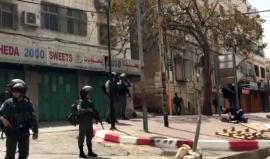 شاب يؤدي الصلاة بين جنود الاحتلال الذين أغلقوا المحلات التجارية وسط الخليل للسماح للمستوطنين باقتحام المنطقةتصوير عامر أبو عرفة