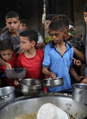 فلسطينيون يتجمعون لتلقي وجبات طعام من مطبخ خيري في مخيم النصيرات وسط قطاع غزة