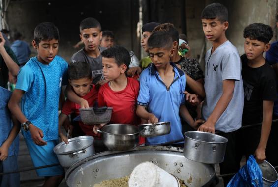 فلسطينيون يتجمعون لتلقي وجبات طعام من مطبخ خيري في مخيم النصيرات وسط قطاع غزة