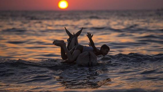 طفل فلسطيني يلهو على شاطئ بحر غزة مع وقت الغروب