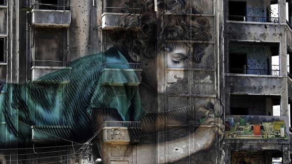 جدارية لطفل يعمل على جهاز الكتروني على مبنى متضرر خلال الحرب الأهلية في بيروت