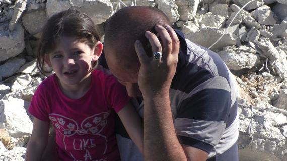 طفلة تقف مع والدها على ركام منزل العائلة الذي هدمه الاحتلال