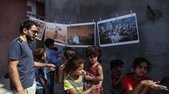 مصور فلسطيني يقيم معرضاً لأعماله المصور على جدران مخيم الشاطئ