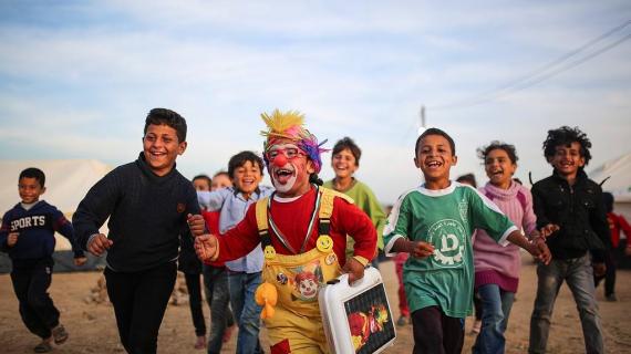 مهرج يقدم عروضا لتسلية الأطفال المشاركين مع عائلاتهم في مسيرة العودة