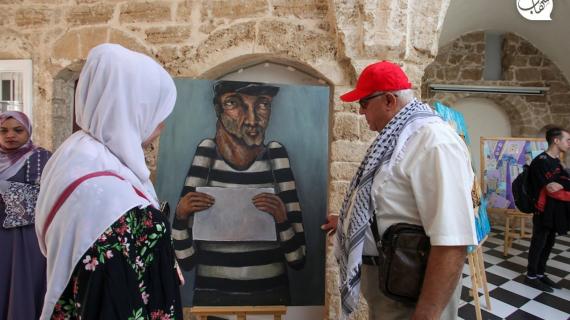 زوار معرض فني أقيم في بيت الغصين الثقافي في مدينة غزة يتجولون بين اللوحات الفنية