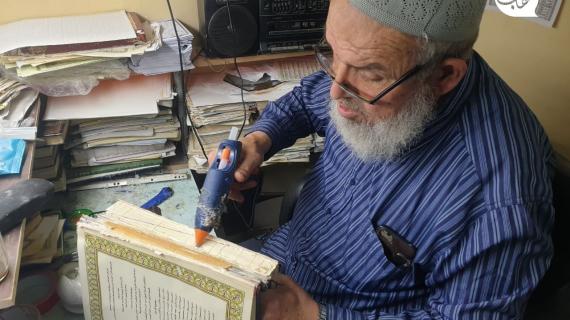 تطوعا ولخدمة كتاب الله.. الحاج هشام برزق يقوم بصيانة المصاحف الممزقة في غرفة صغيرة داخل أحد مساجد مدينة غزة