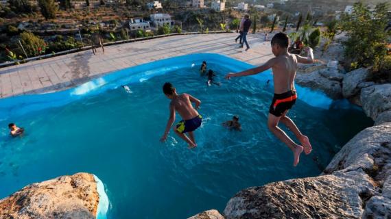 عائلة فلسطينية تحول كهفًا في أرضها لبركة سباحة هربا من الأجواء الحارة في بلدة بلعين غرب رام الله