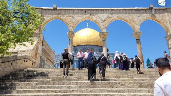 فلسطينيون يسيرون أمام قبة الصخرة داخل مجمع المسجد الأقصى في القدس
