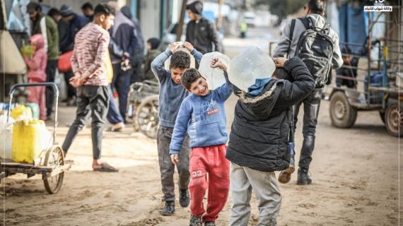 أطفال يملؤون دلاءهم بالمياه التي توزعها صهاريج المياه وينقلونها إلى خيام نزوحهم في مخيم النصيرات